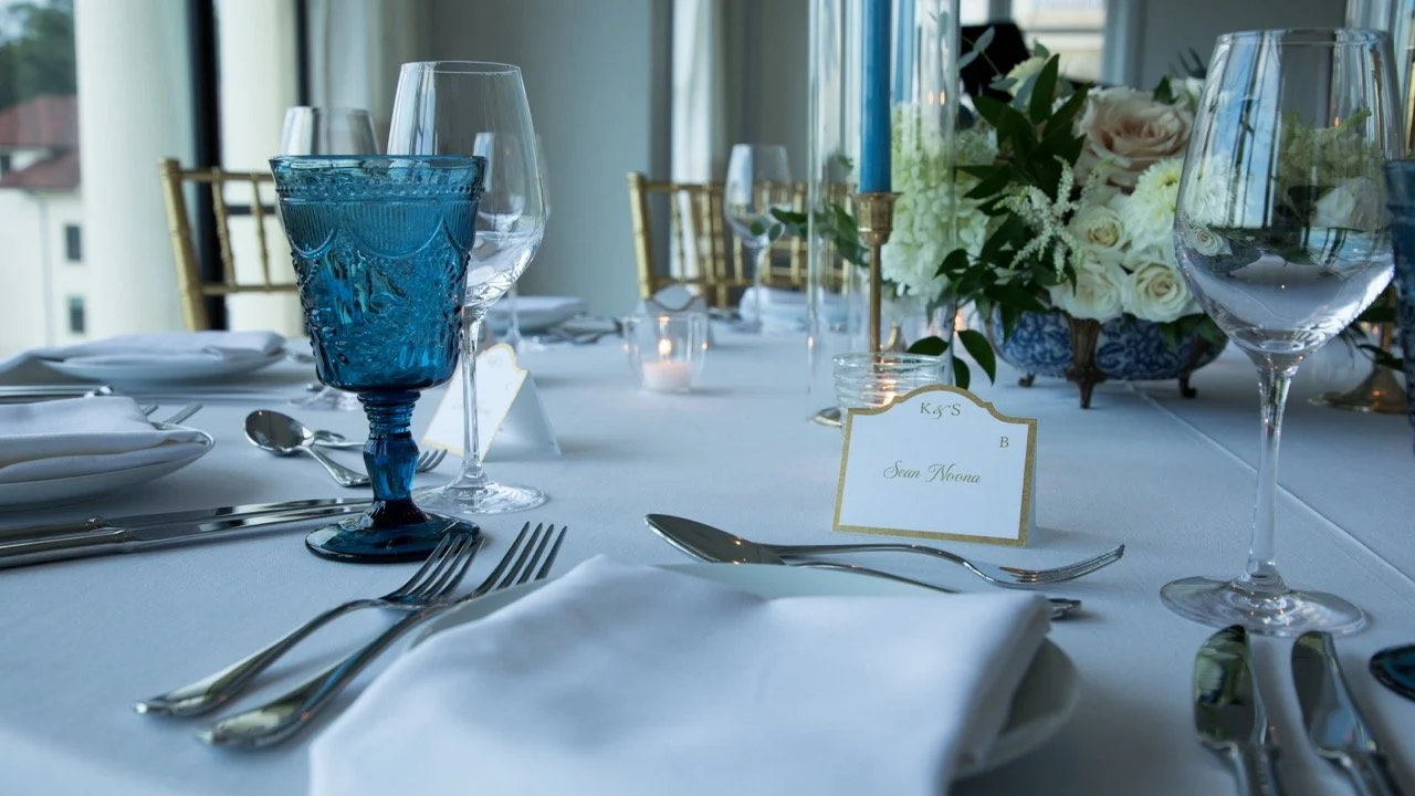 Luxury rehearsal dinner table setup showcasing intricate blue vintage glassware and tall tapered candles in Charlottesville, VA.