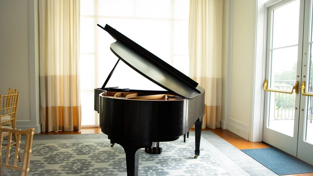 A beautiful black grand piano positioned near light-filled windows in a luxury Charlottesville, Virginia event space.