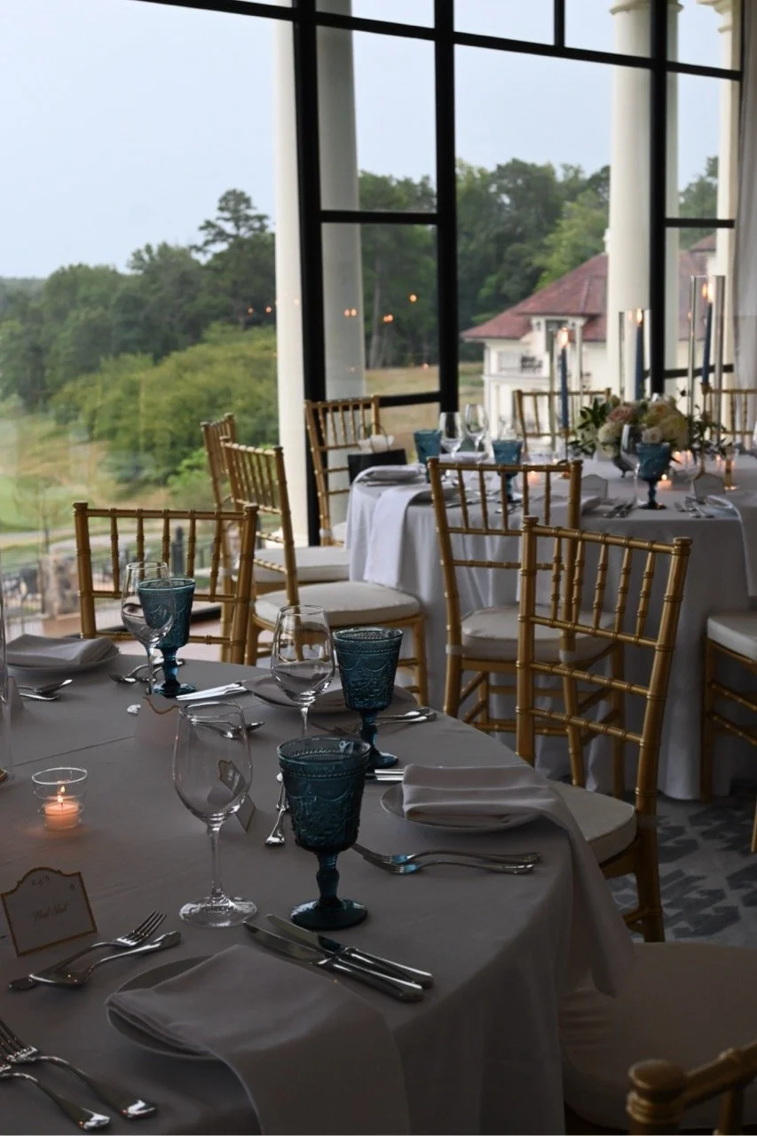 White and green floral centerpieces paired with tall blue candles at a refined Charlottesville rehearsal dinner table.