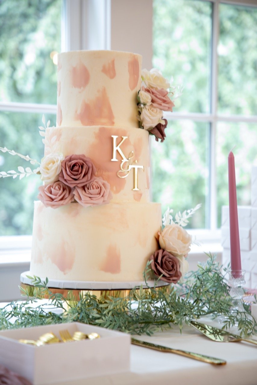 A beautiful three-tier wedding cake decorated with fresh roses and Kareese and Tristan's initials at the Woman's Club of Portsmouth.