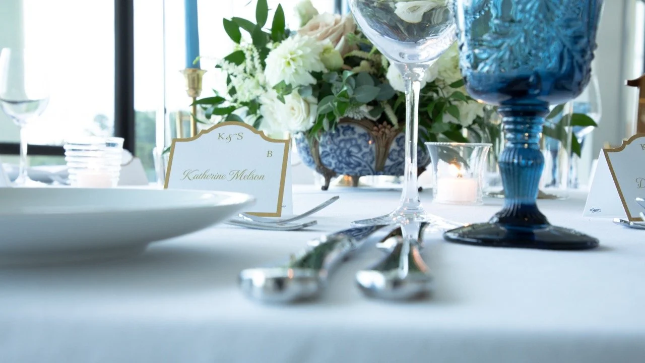 Upscale table setting details featuring fine silverware, custom place cards, and crisp blue candles at a Virginia wedding event.
