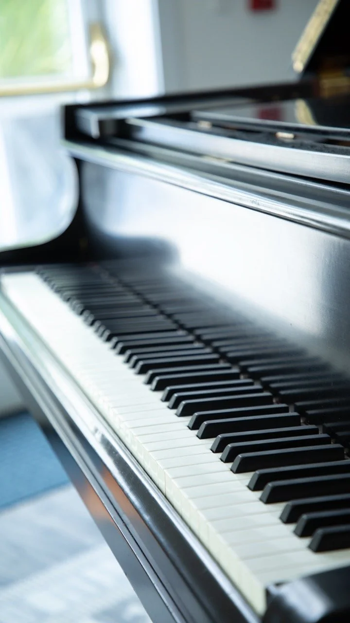 Black and white crisp detail of a grand piano keyboard at an upscale wedding cocktail hour venue.