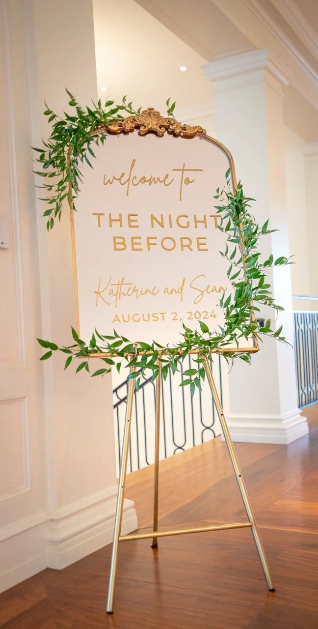 Elegant gold-framed "Welcome to The Night Before" signs with greenery for Katherine and Sean's rehearsal dinner in Charlottesville, VA.
