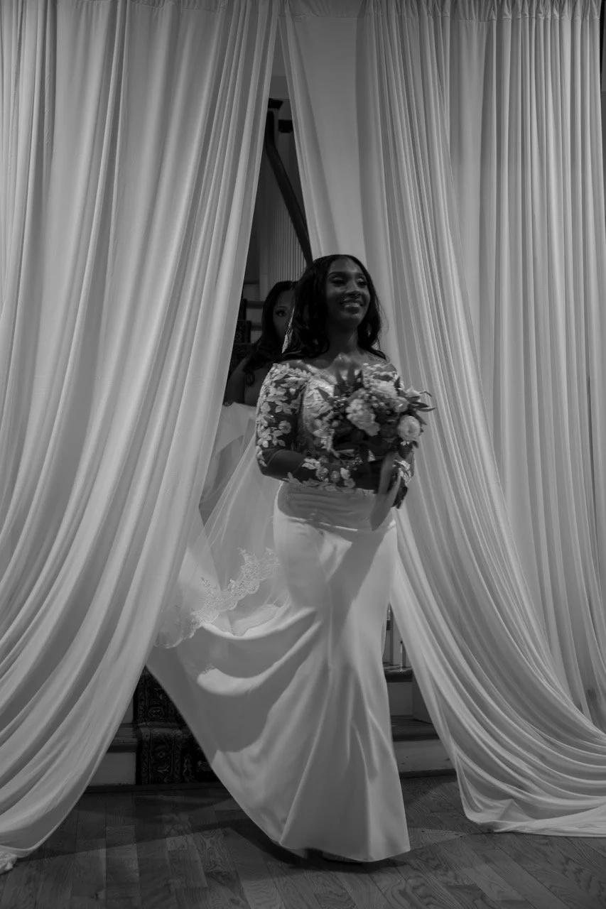 Bride Kareese holding her bouquet while standing within elegant white drapery at the Woman's Club of Portsmouth.

