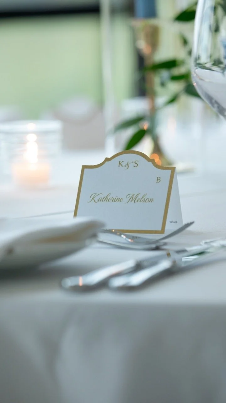 Close-up macro photo of a personalized elegant gold-trimmed reception place card at a Charlottesville wedding rehearsal dinner.