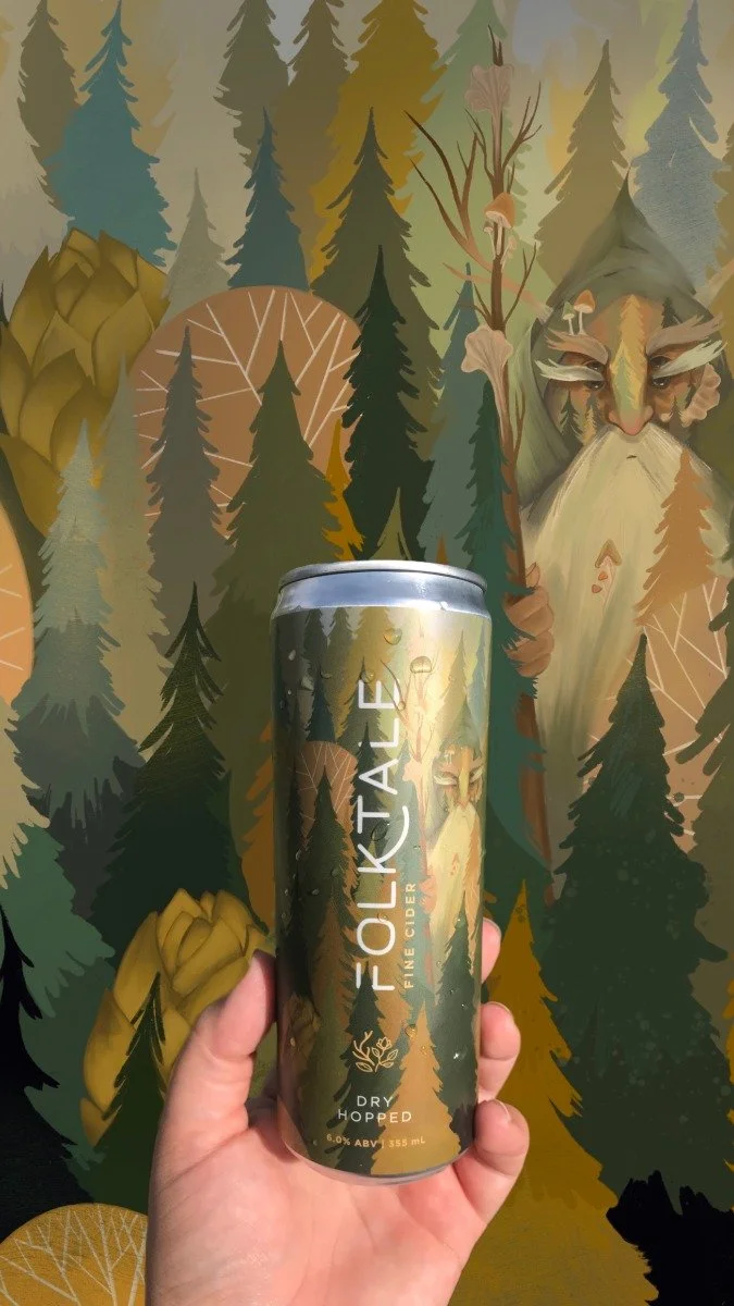 Hand holding a can of Folk Tale Fine Cider with a forest-themed background featuring a large, stylized image of a mystical face and tall pine trees.
