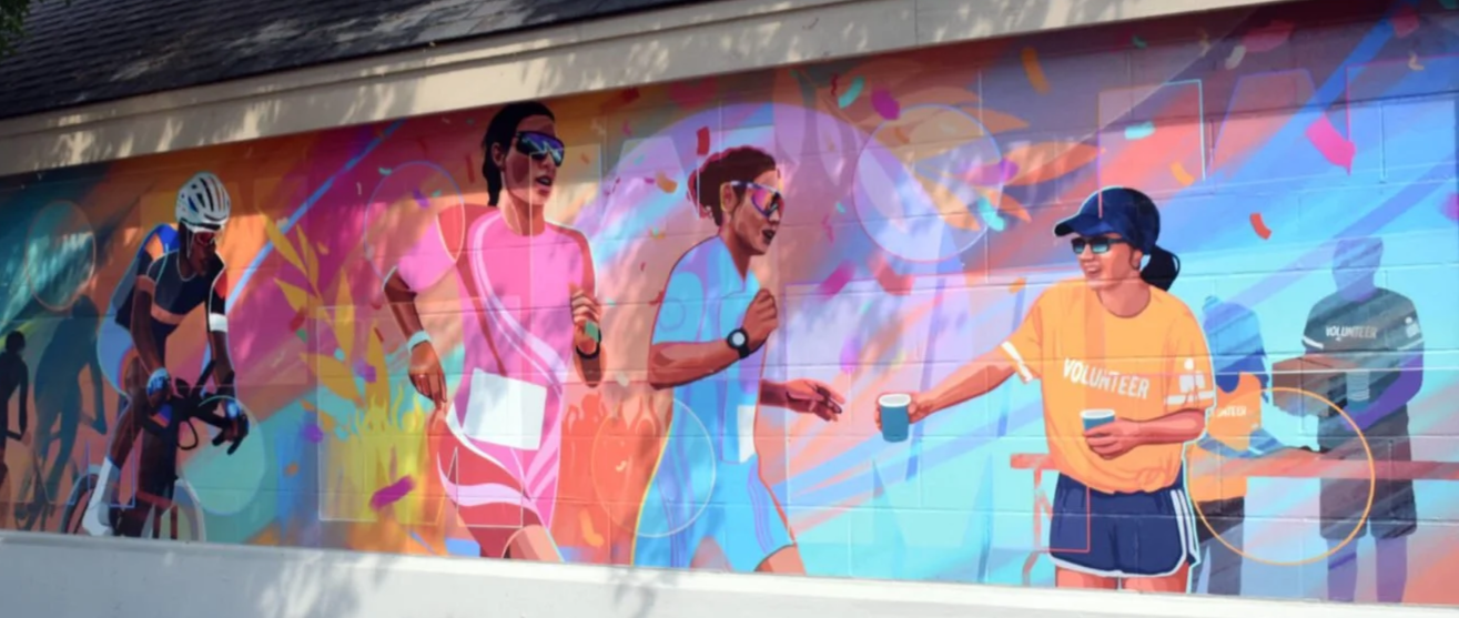 Murale depicting runners participating in a race, with a volunteer handing out water. Ironman Canada, Penticton BC, Liz Grace Studio, Liz Dumontet.