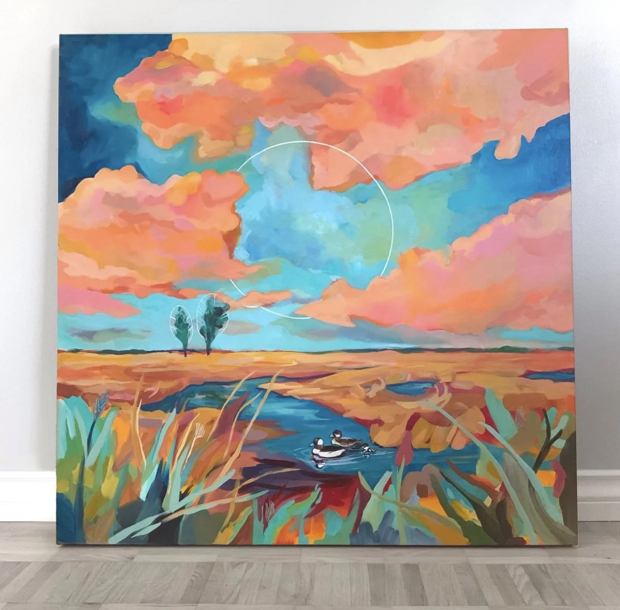 Colorful landscape painting of a sky with pink, orange, blue, and purple clouds, a pond with three ducks, tall grasses, and distant trees.