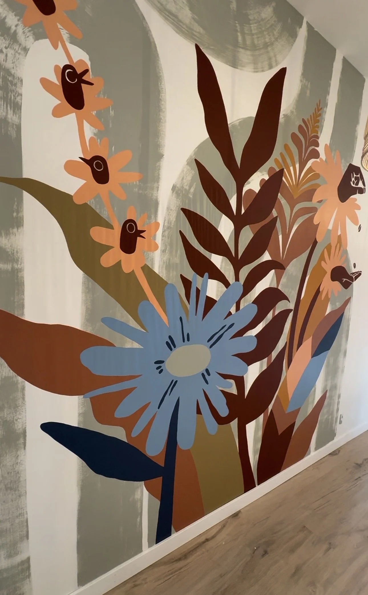 Colorful floral wall art featuring stylized flowers and leaves in shades of orange, brown, blue, and green.