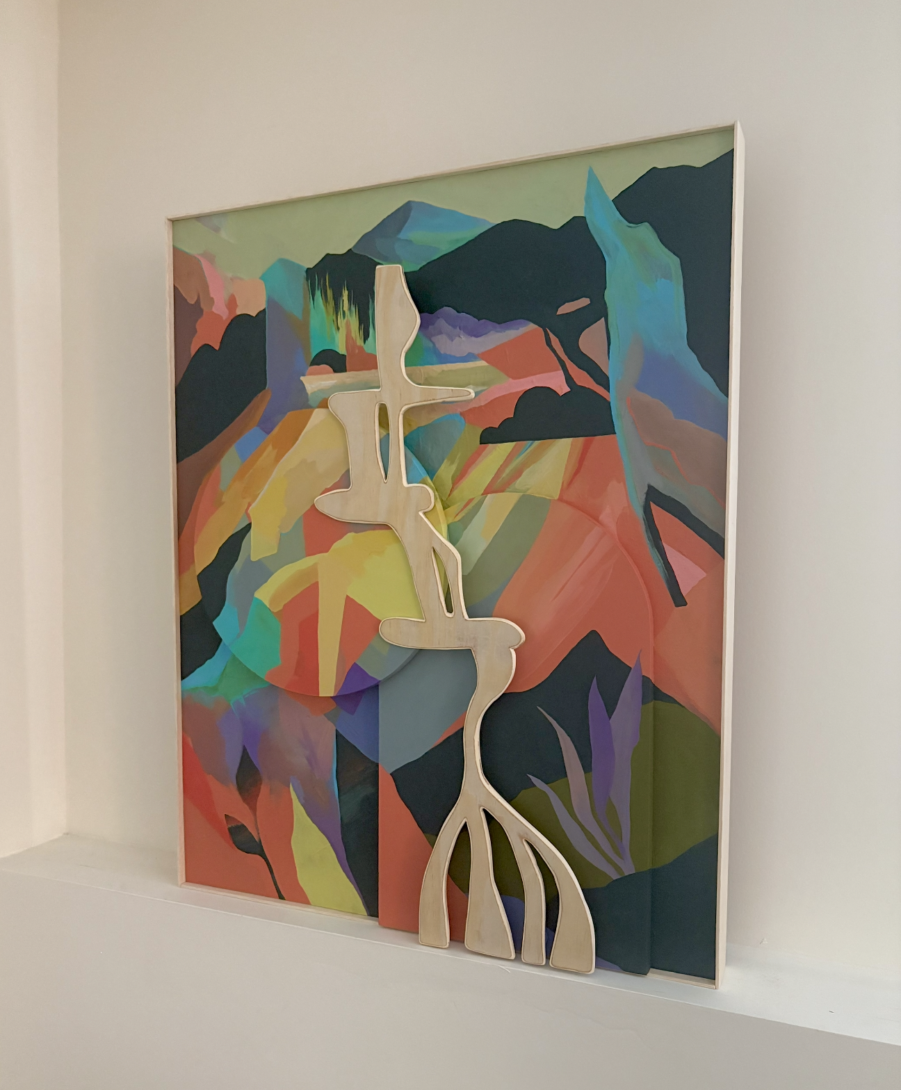 A colorful abstract landscape painting with shades of green, orange, blue, and purple, featuring a wooden cutout of a waterfall shape layered on top.