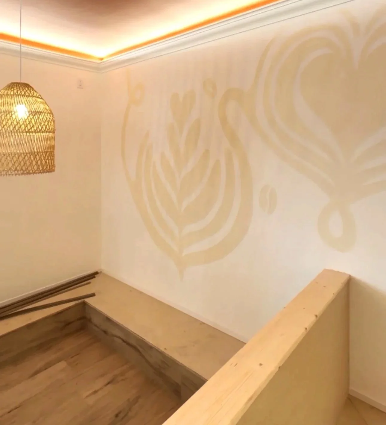 Interior corner of a room with beige walls, wooden bench, and a wicker pendant light casting decorative shadows on the wall.Bright Jenny Coffee, Kelowna BC, Liz Grace Studio, Liz Dumontet.