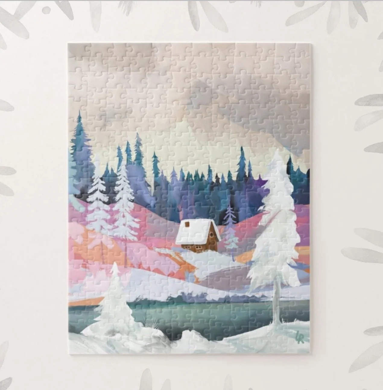 A completed jigsaw puzzle depicting a winter landscape with snow-covered trees, a small wooden cabin, a frozen lake in the foreground, and a mountain range in the background, with a soft pastel-colored sky.