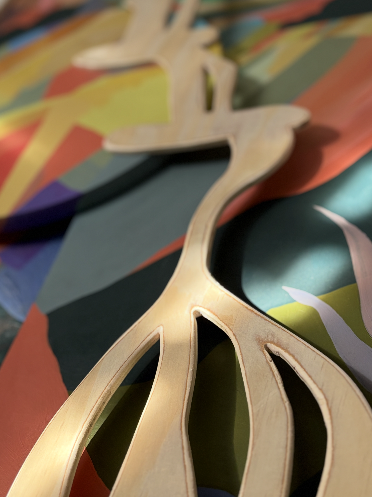 A wooden cutout of a waterfall on colorful abstract painting