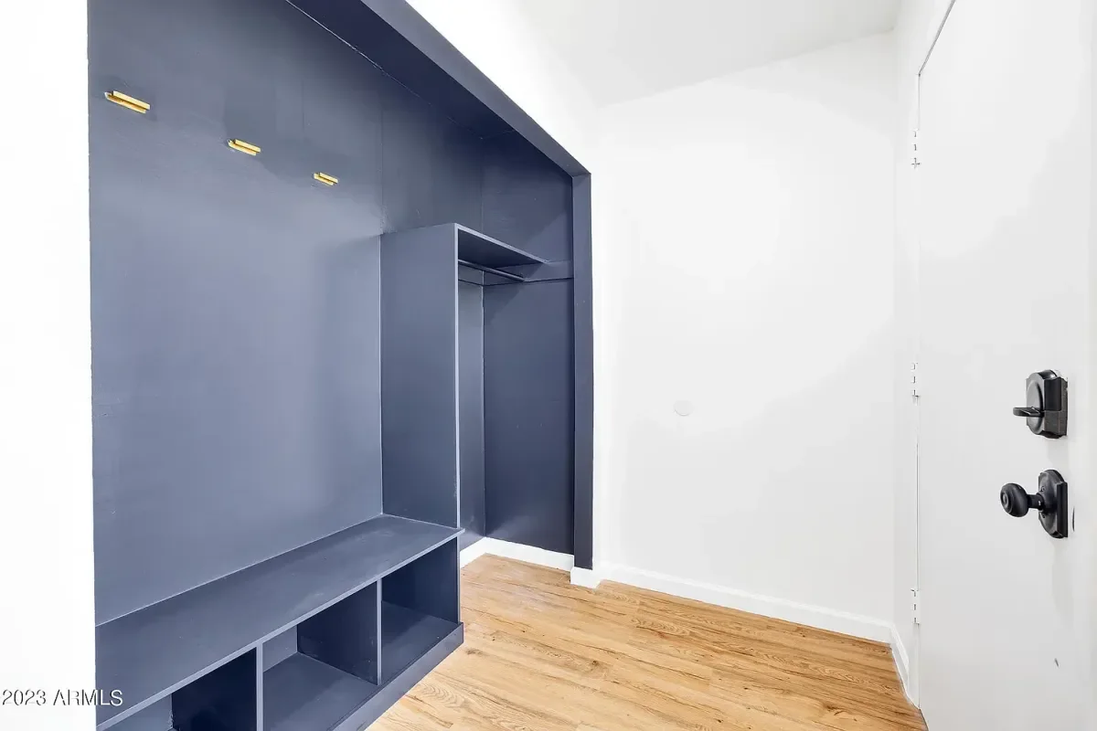 Mudrrom. interior entryway with dark blue built-in storage bench and hooks, white walls, and a light wood floor.European Design. Interior Design. Dallas. Highland Park. North Dallas. Great room. renovation. Remodel. custom craftsmanship. Timeless.