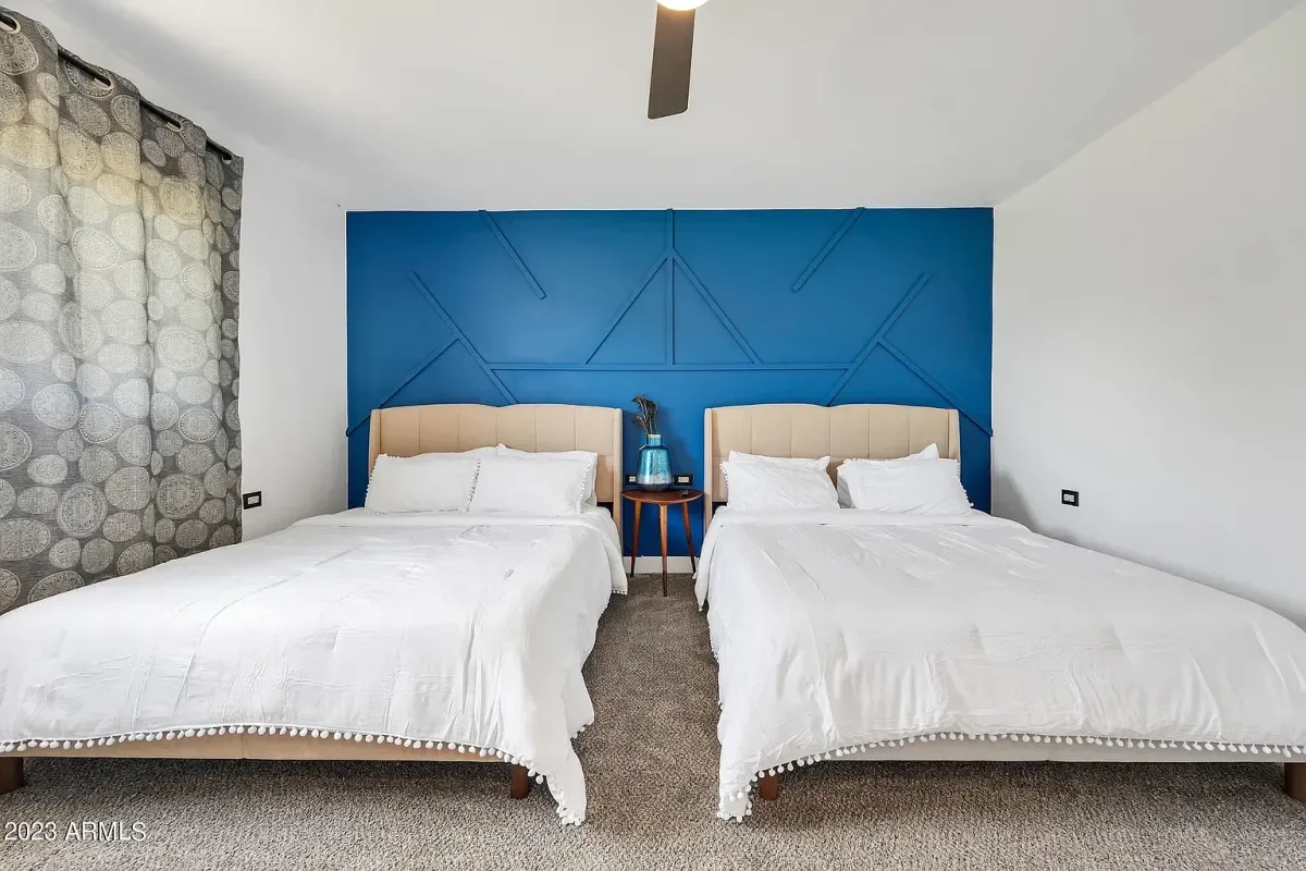 A bedroom with two queen beds with white bedding and beige headboards, a blue accent wall behind the beds with texture and pattern added. European Design. Interior Design. Dallas. Highland Park. North Dallas. Great room. renovation. Remodel.
