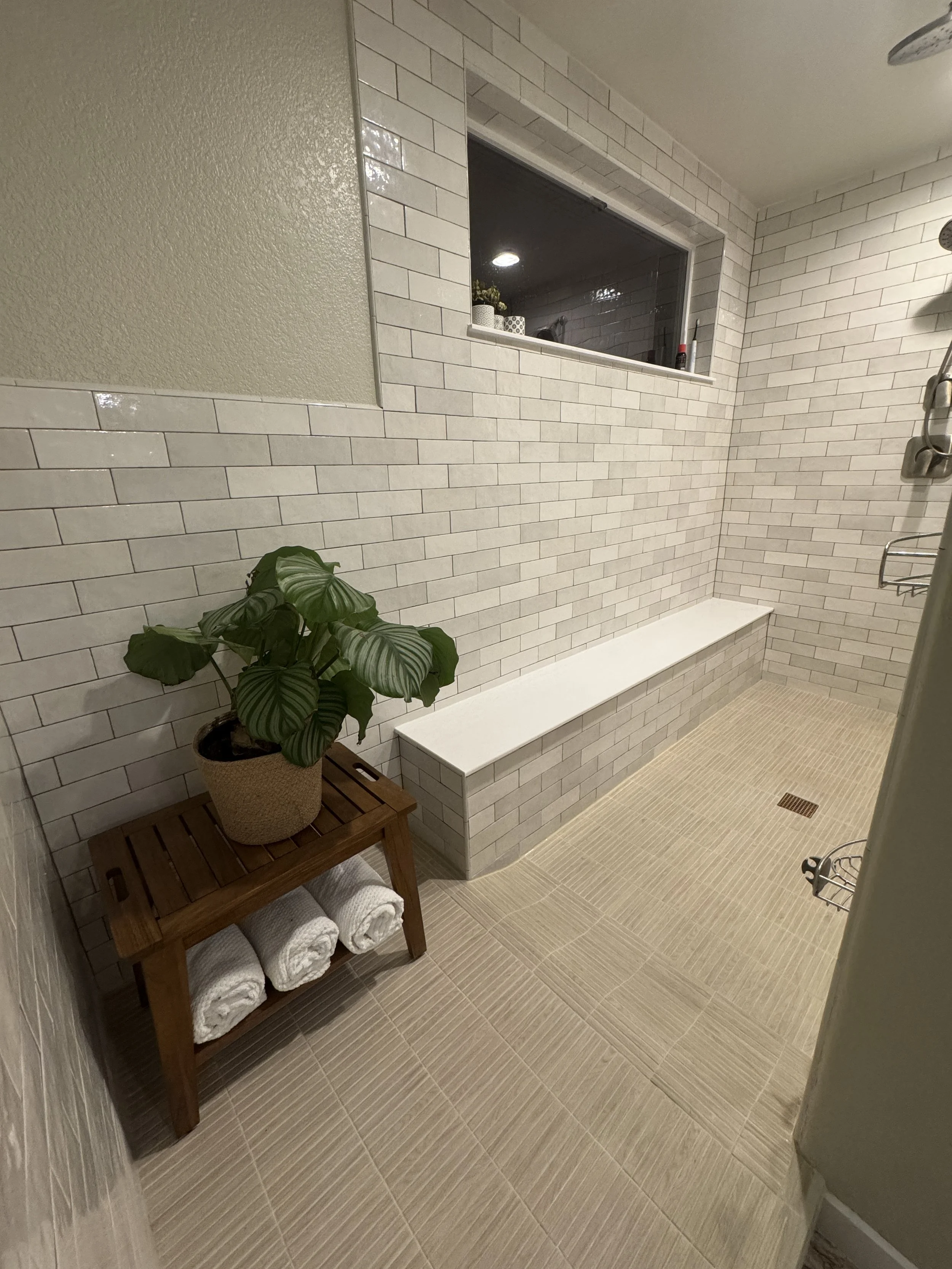 A modern shower area with beige tiled floor and white brick walls. European Design. Interior Design. Dallas. Highland Park. North Dallas. Great room. renovation. Remodel. custom craftsmanship. Timeless.