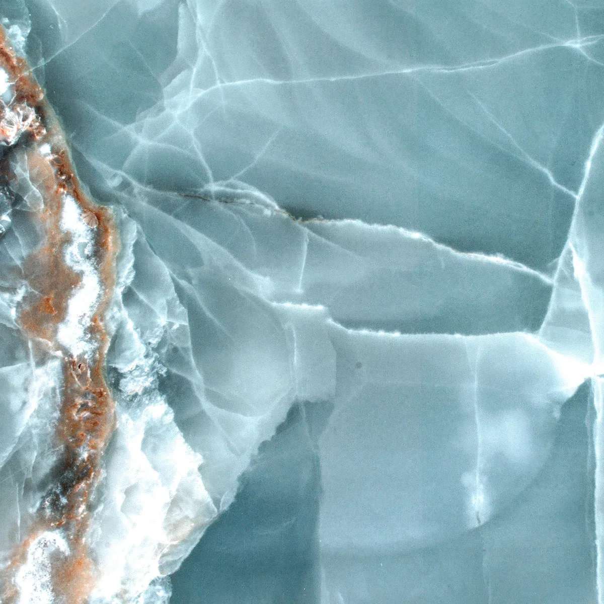 Close-up of a cracked blueish-green marble surface with some brownish-orange streaks.