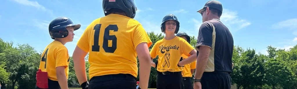 Group of youth baseball players in yellow jerseys and helmets, listening to coach or referee during game or practice outdoors on sunny day.