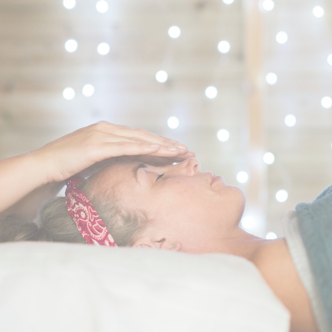 A person lying down receiving reiki or energy healing, with fairy lights in the background.