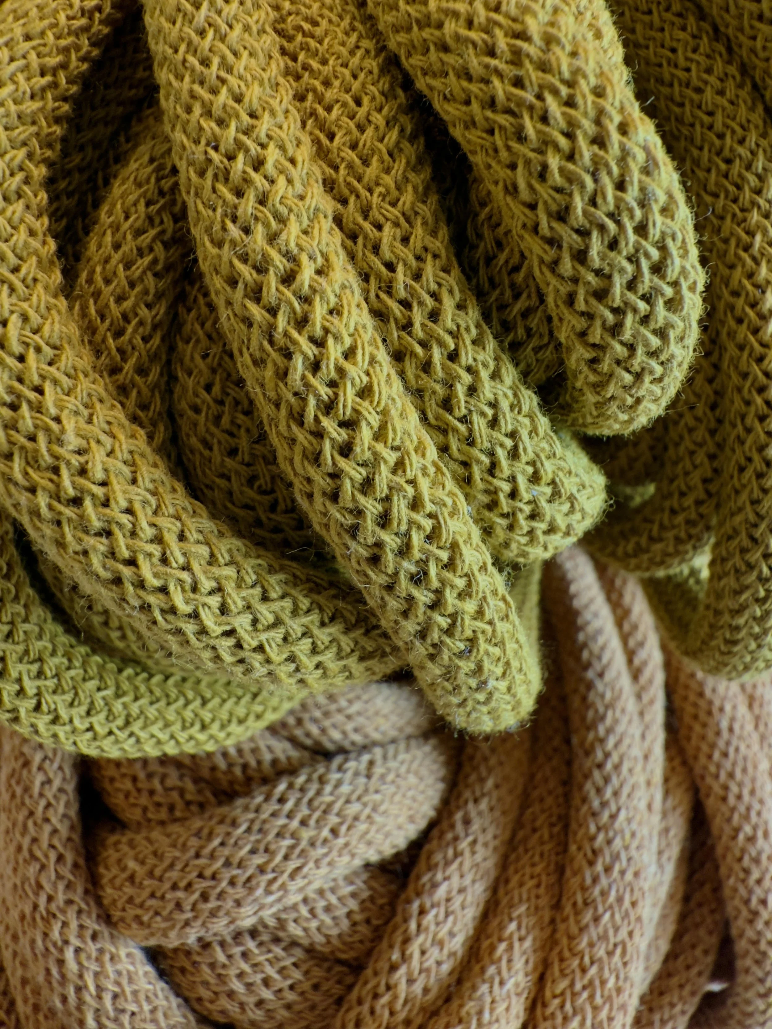 Close-up of intertwined yellow and beige braided cotton rope.