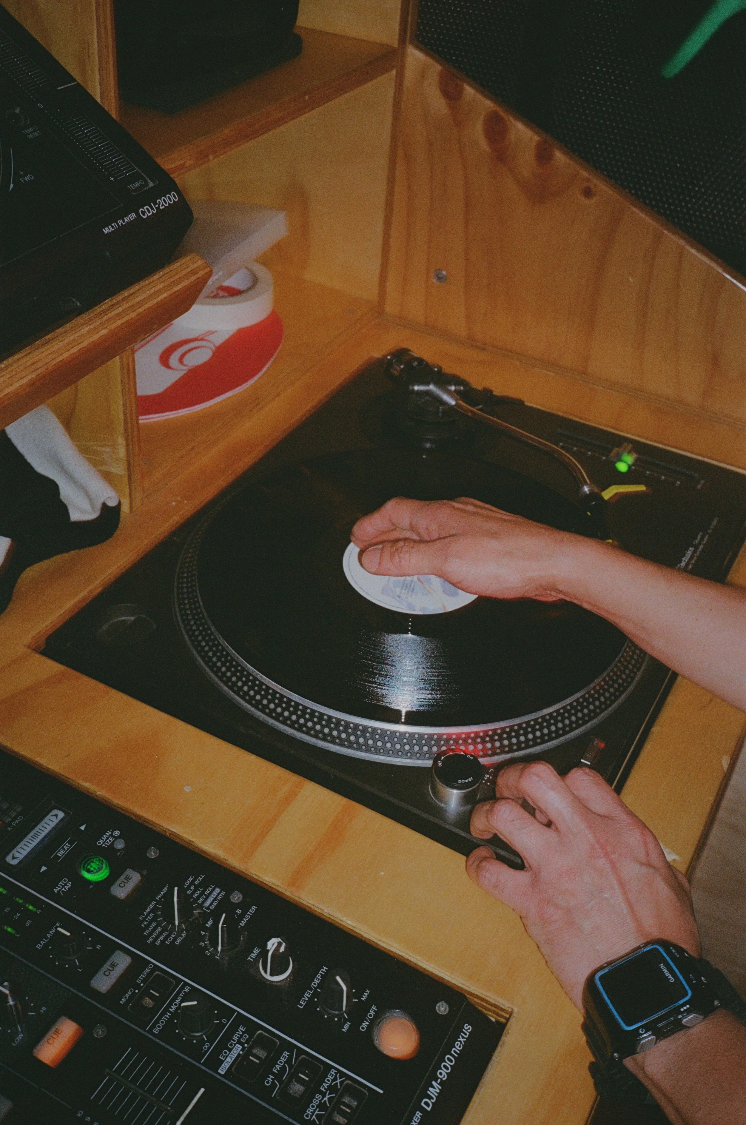 Person placing a vinyl record on a turntable in a DJ setup.