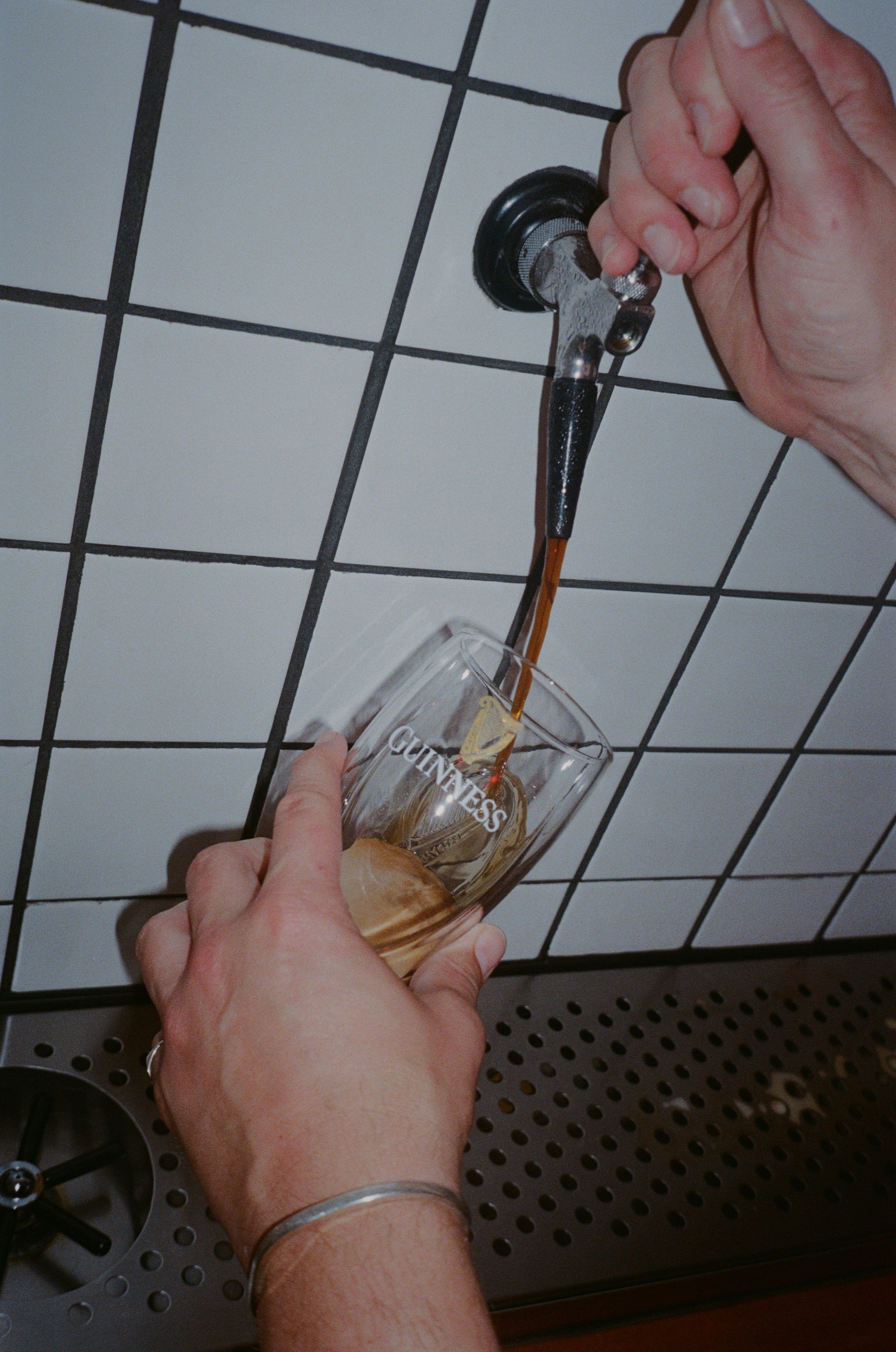 Person pouring beer from tap into a Guinness glass.