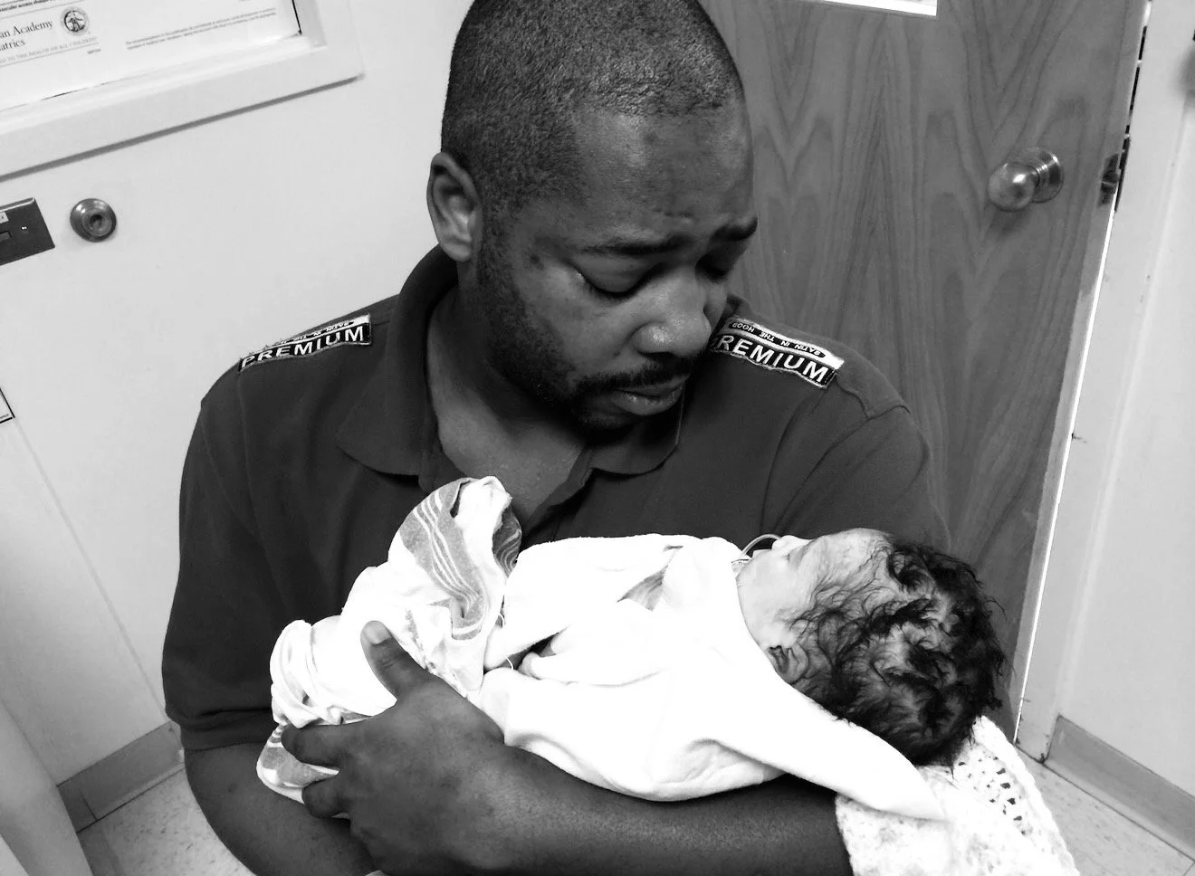 A man in a uniform holding a newborn baby who passed away in a hospital room.