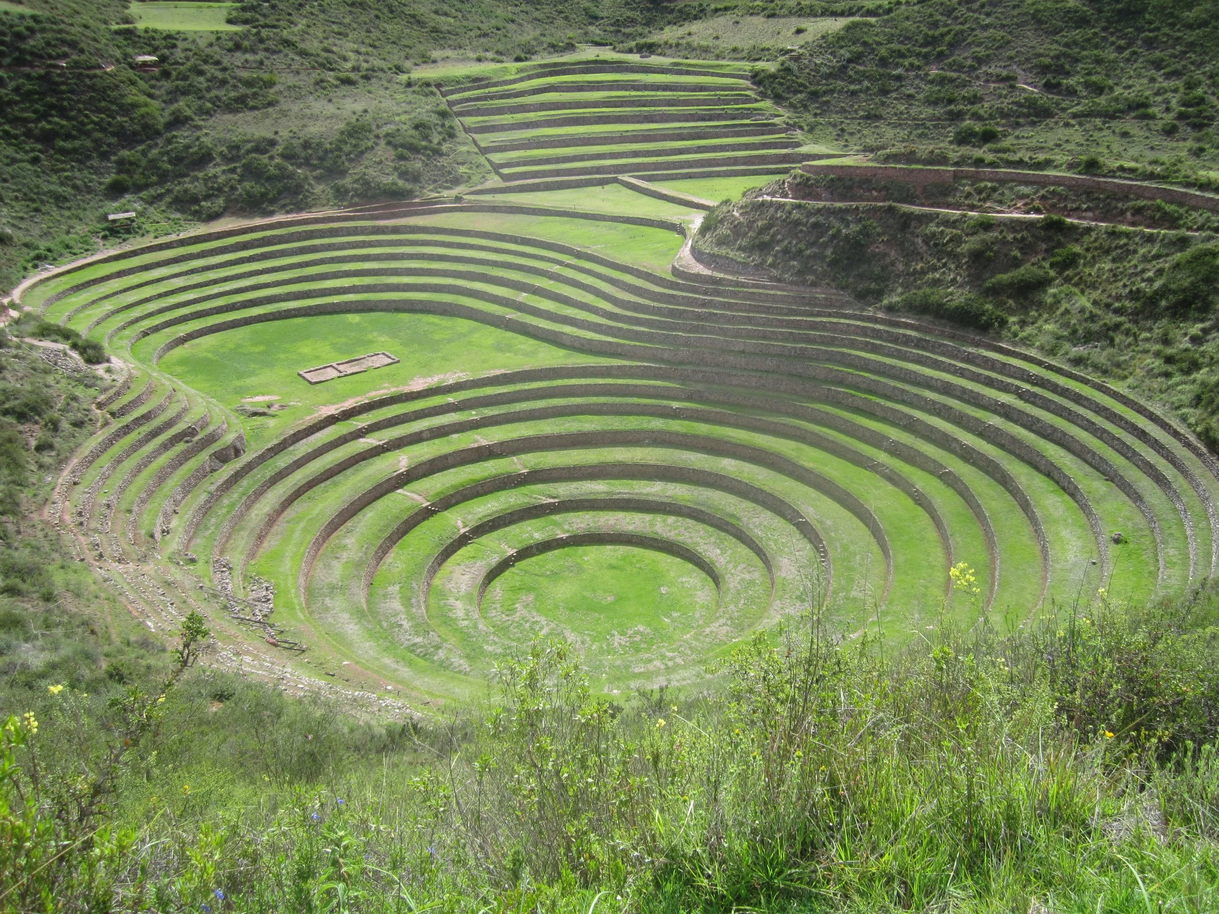 Ancient Incan site with circular terraces in a green valley.