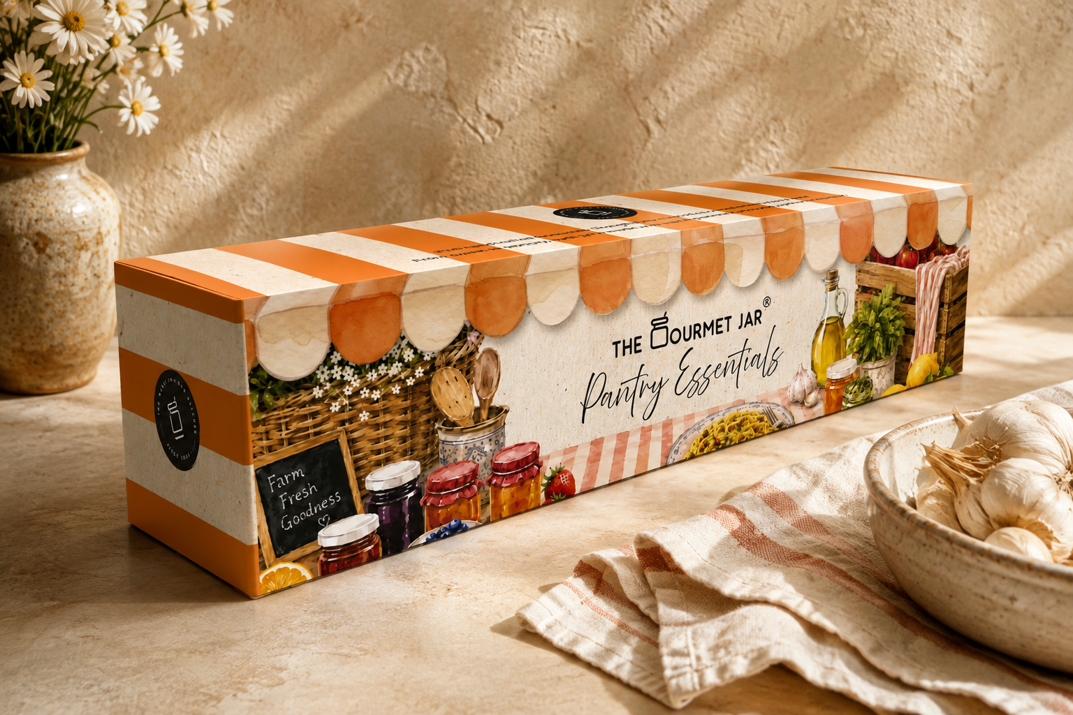The Gourmet Jar Pantry Essentials gift box styled in a farmer's-market setting, showing the striped awning motif and watercolour packaging illustrations