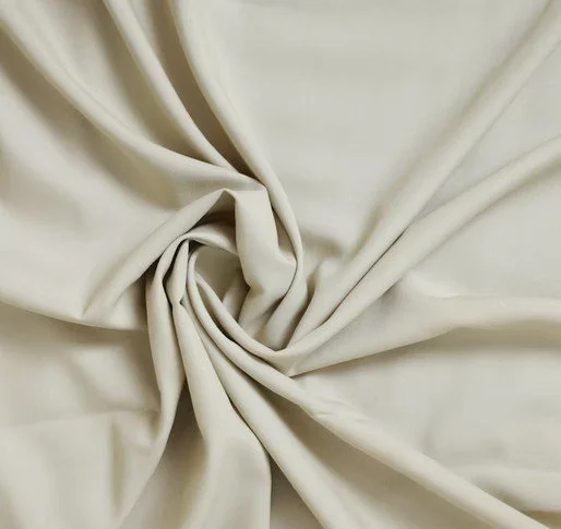 Nahaufnahme eines cremefarbenen Stoffes, der zu einer Schleife gebunden ist.