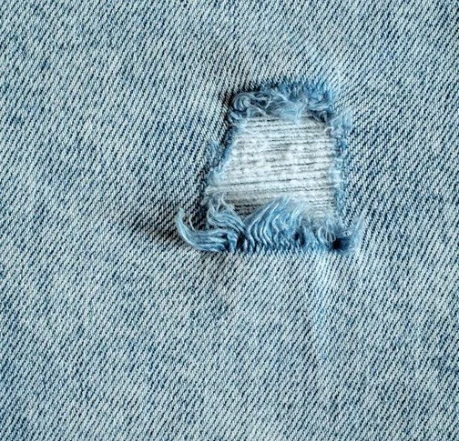 Nahaufnahme einer Jeans mit einem großen Riss