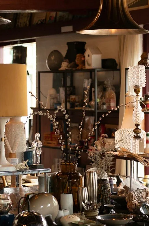 Ein Raum mit verschiedenen dekorativen Gegenständen, darunter Vasen, Lampen, Skulpturen und Pflanzen, in einer gemütlichen Einrichtung.