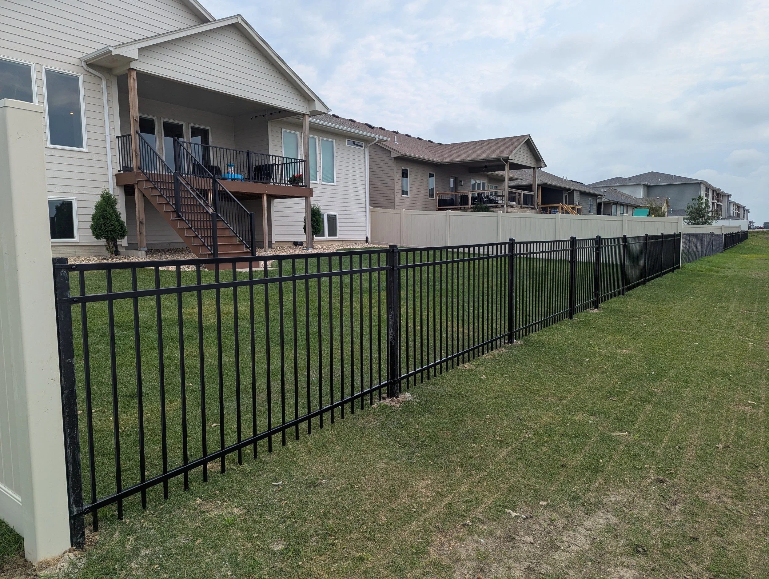 An ornamental iron fence installed on the back line of a neighborhood house.