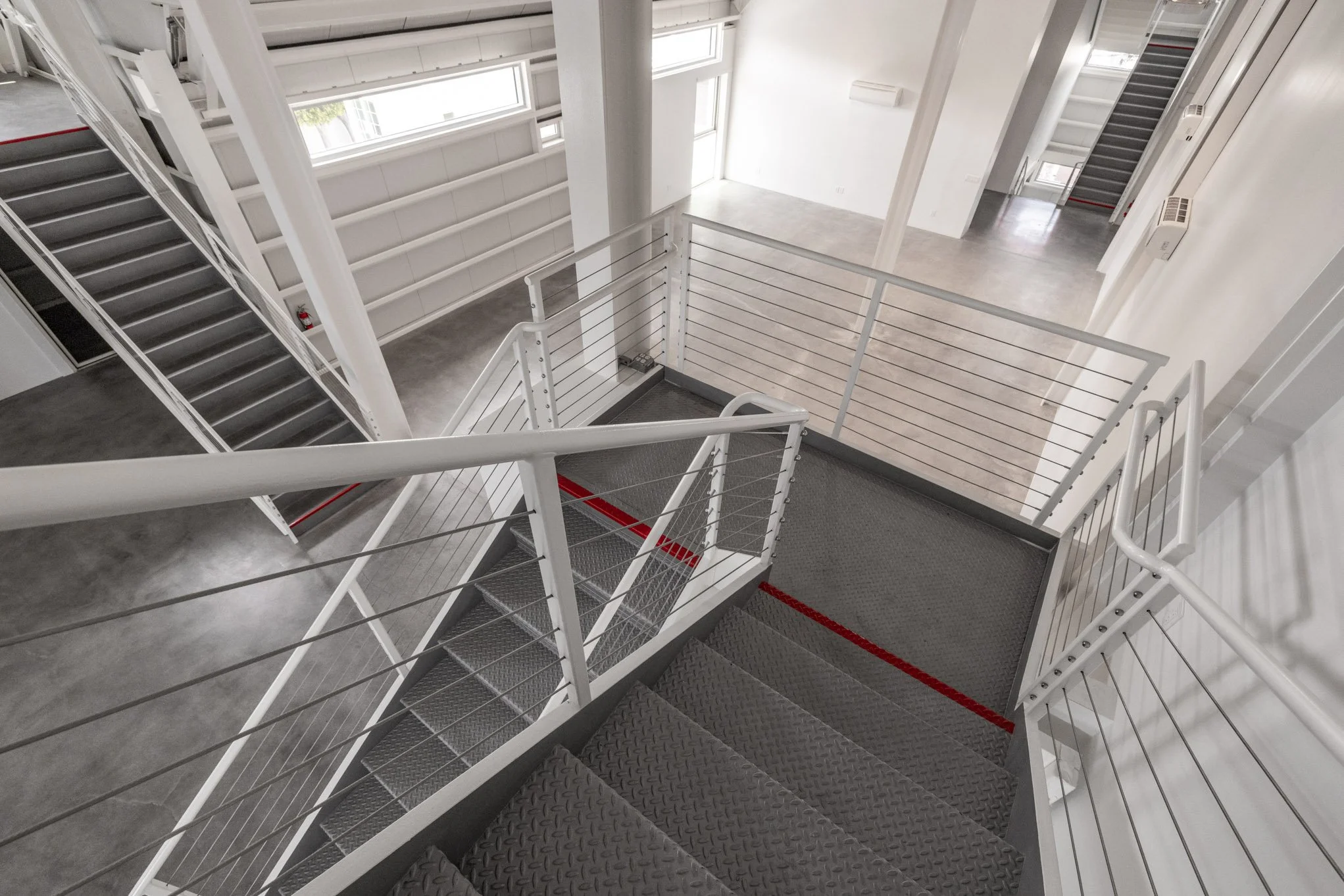 Indoor staircase with metal steps and white railings in a modern, minimalistic building