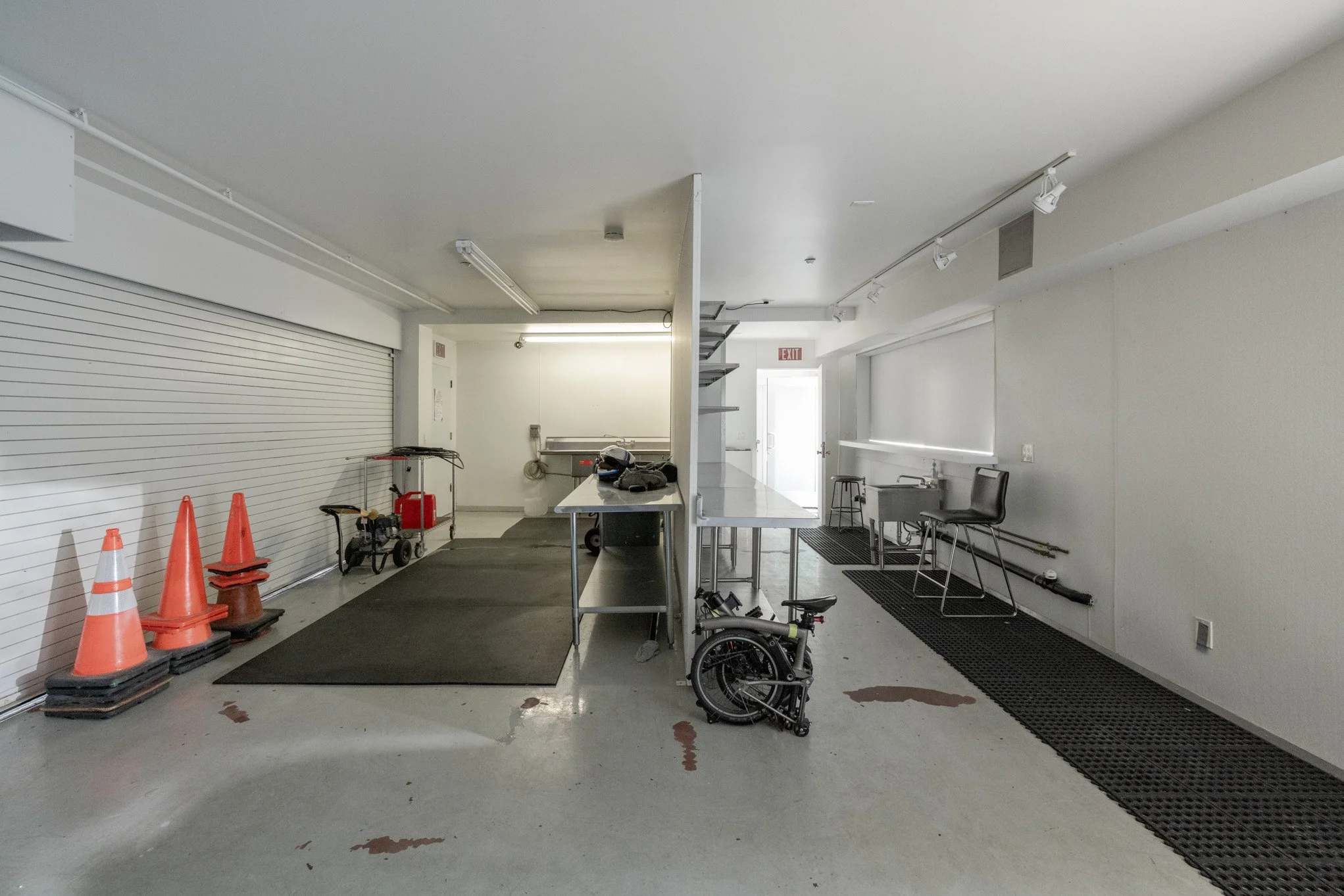Empty commercial space with tools, cones, wheelchairs, and work tables inside.