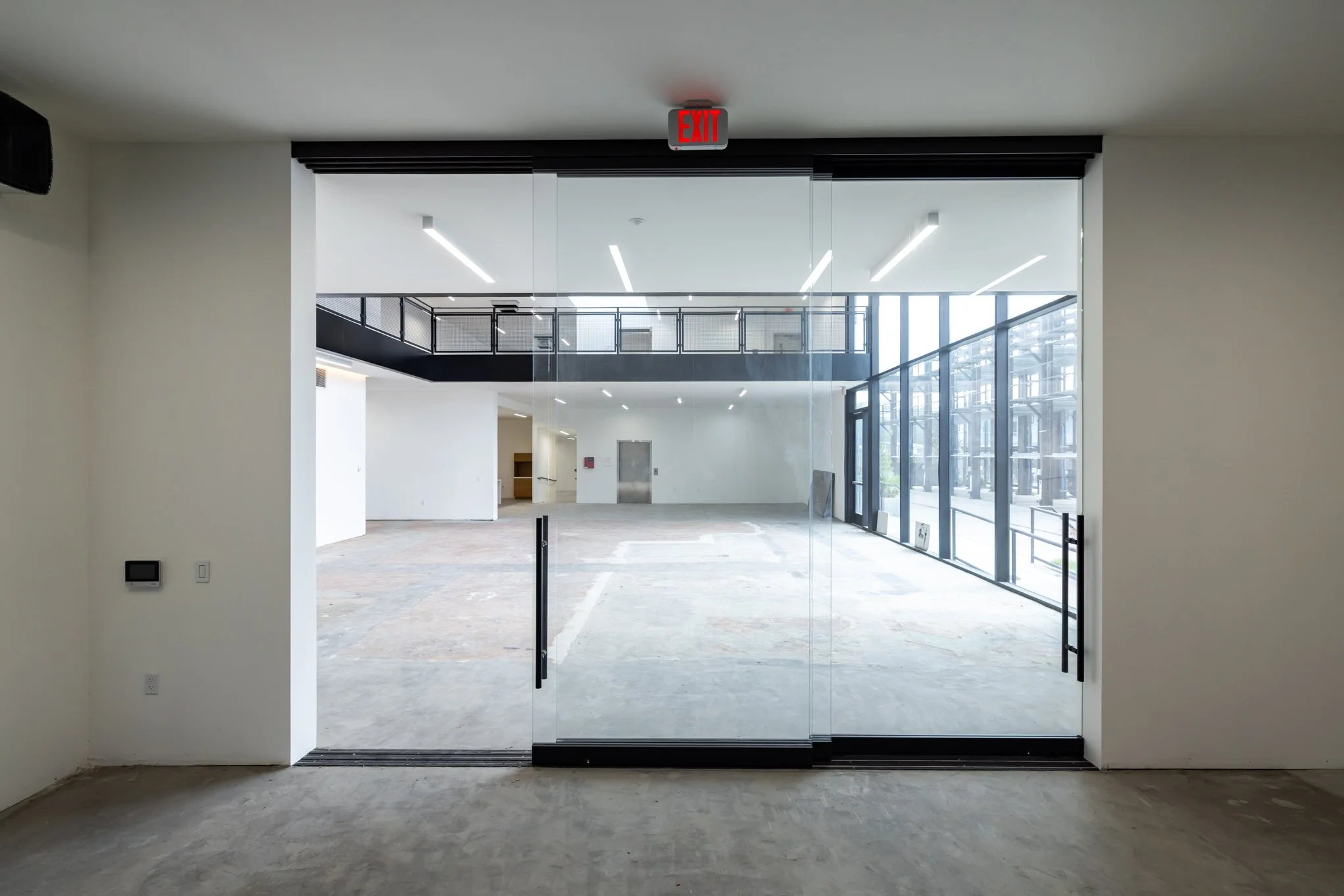 Empty commercial space with glass doors, large windows, and modern lighting.