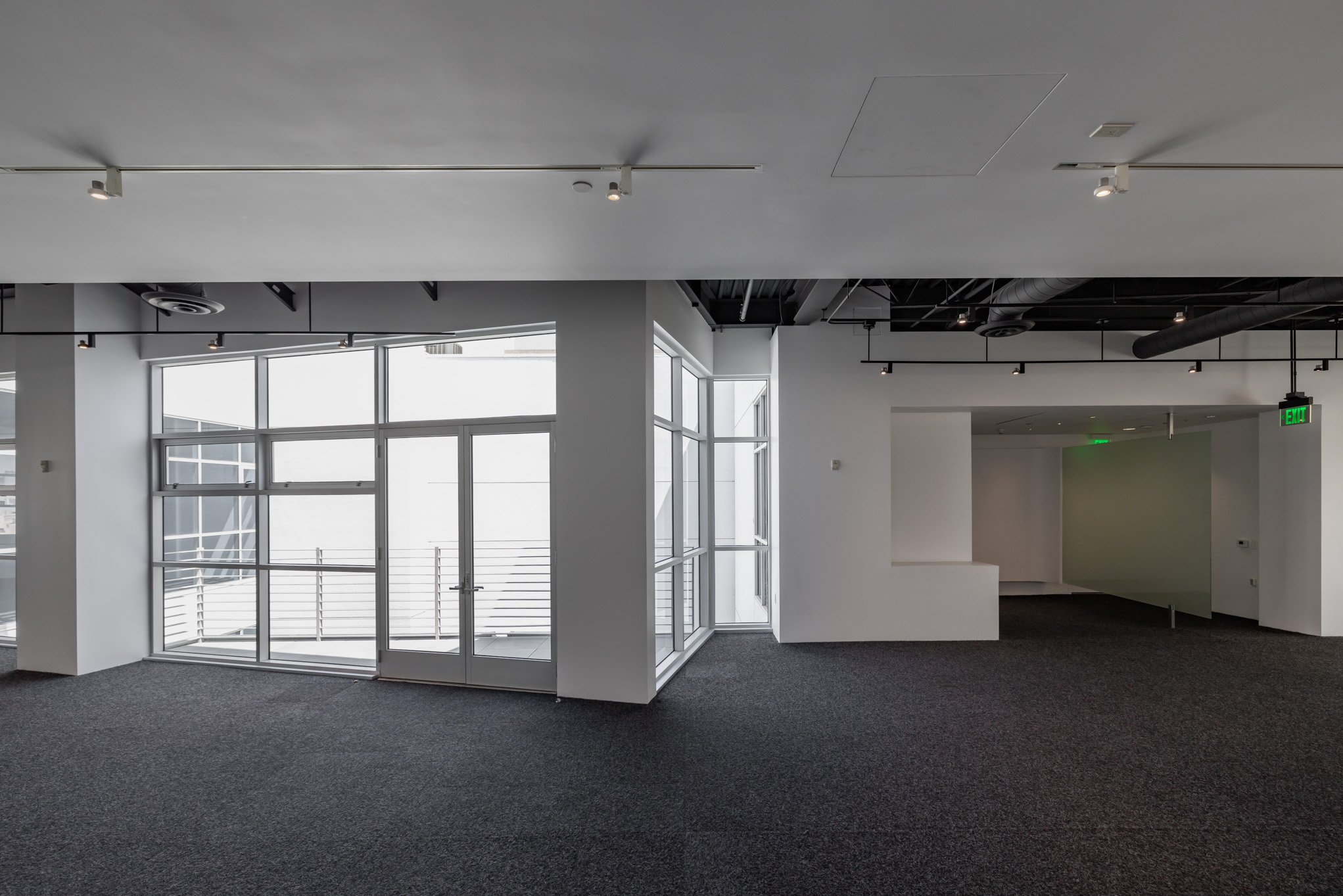 Empty modern office interior with large windows and gray carpet.