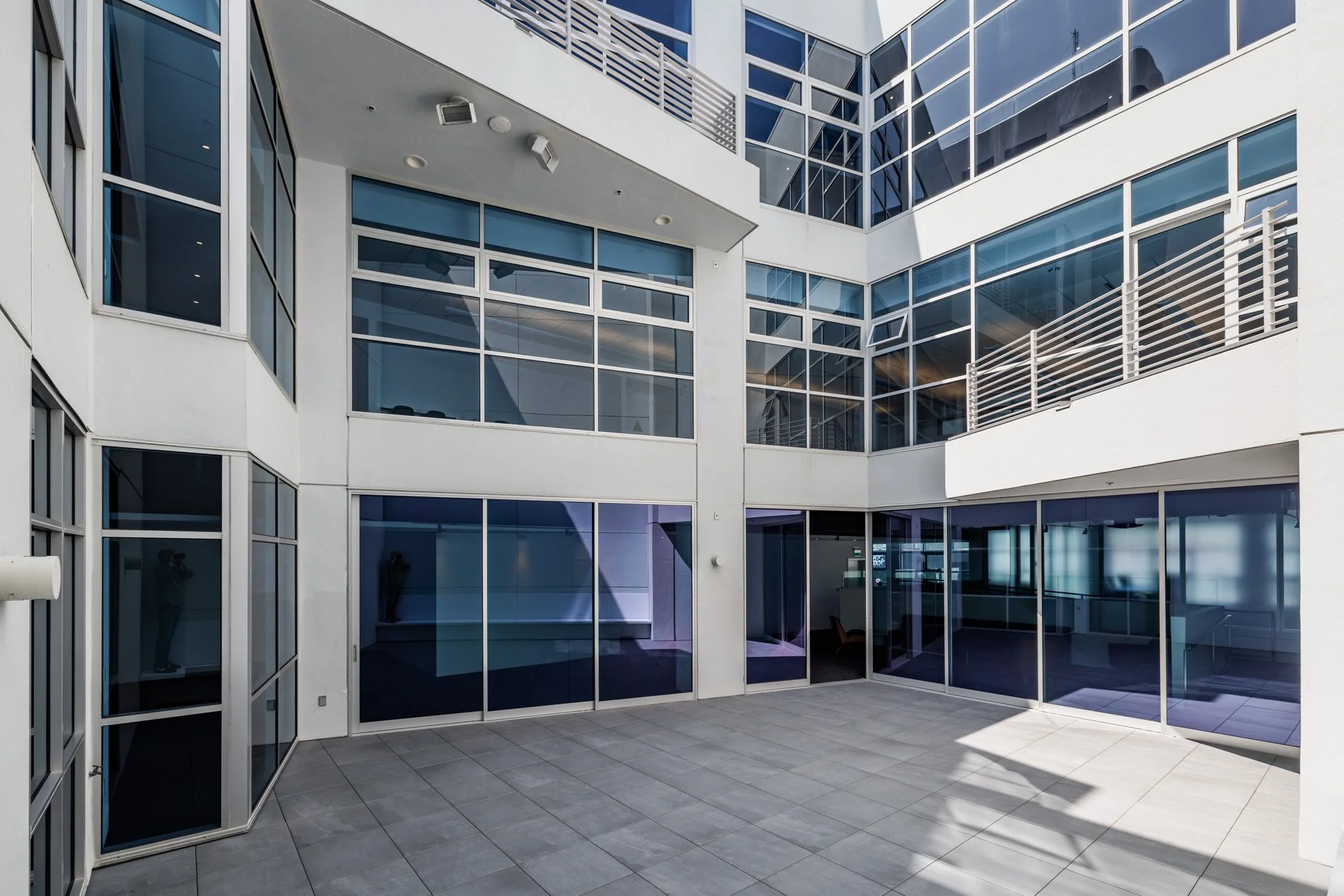 Empty modern courtyard with large glass windows and white walls in a multi-story building