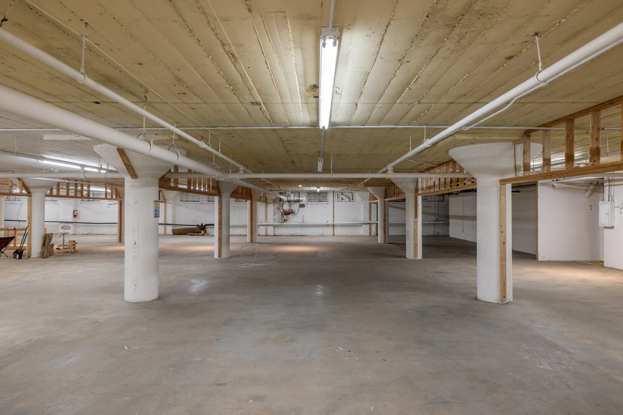 Empty underground parking garage with concrete pillars and unfinished walls.
