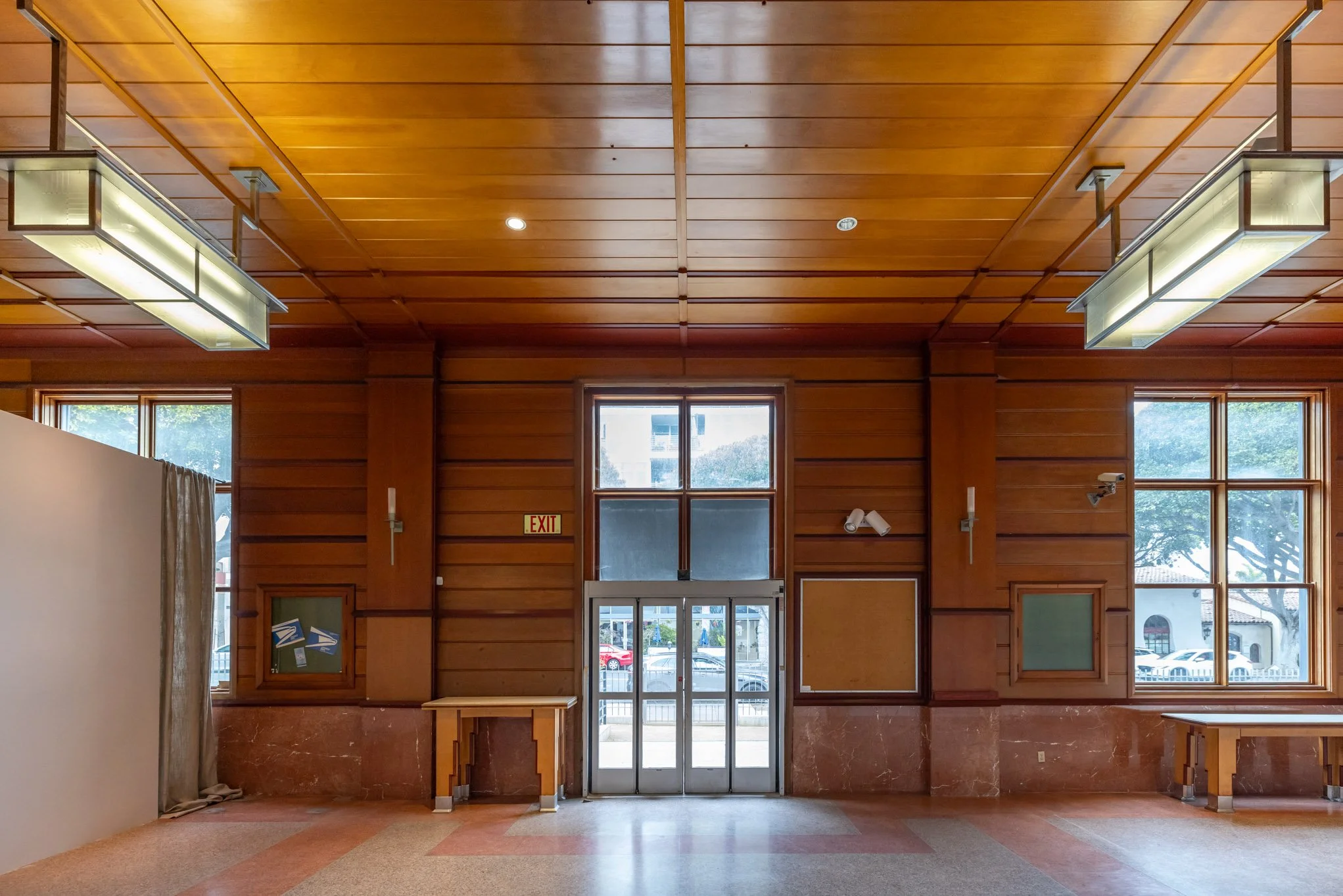 Wood-paneled interior with exit door in center, two windows on sides, and ceiling lights.