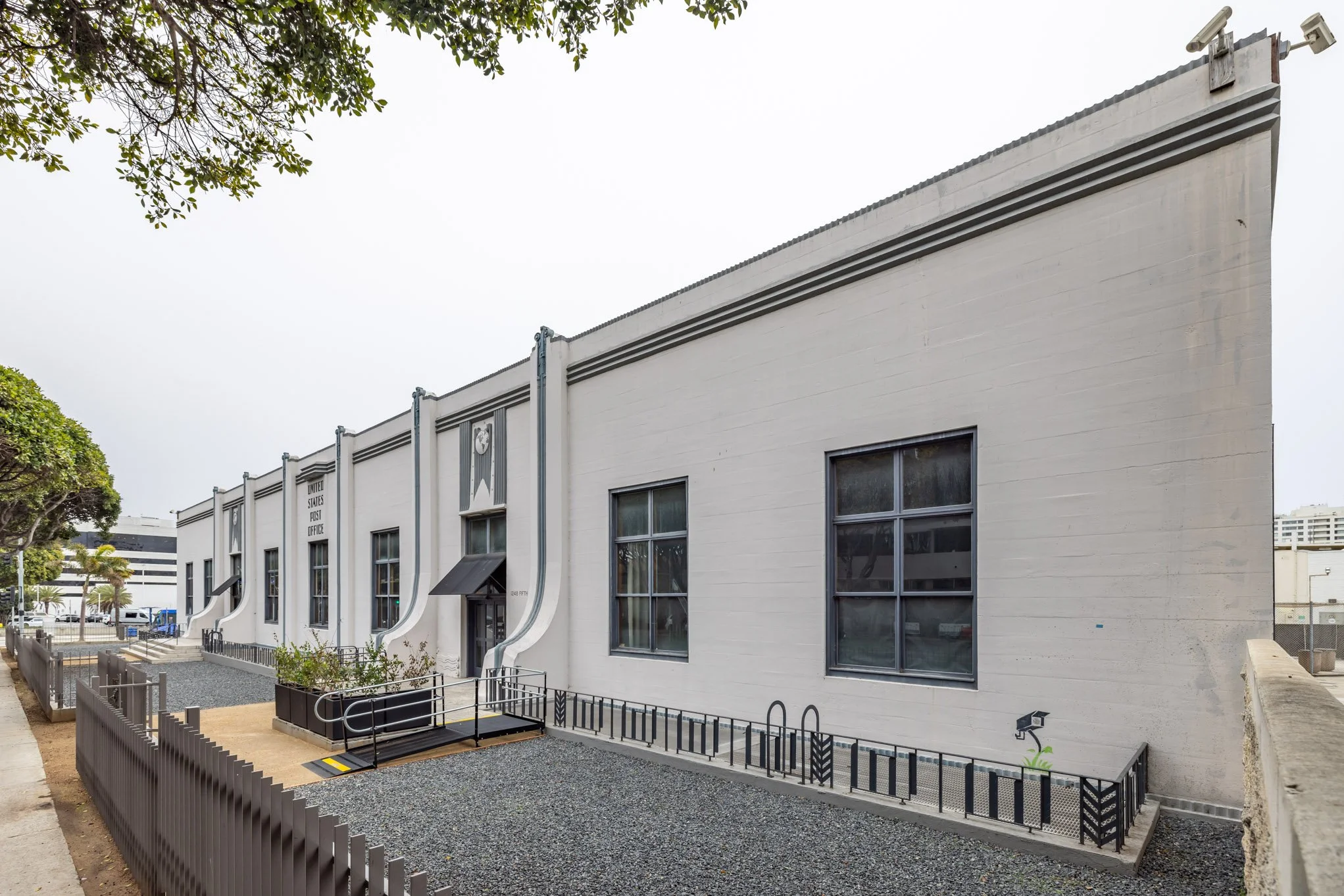 United States Post Office building with a white exterior, four windows, and black decorative railings outside.