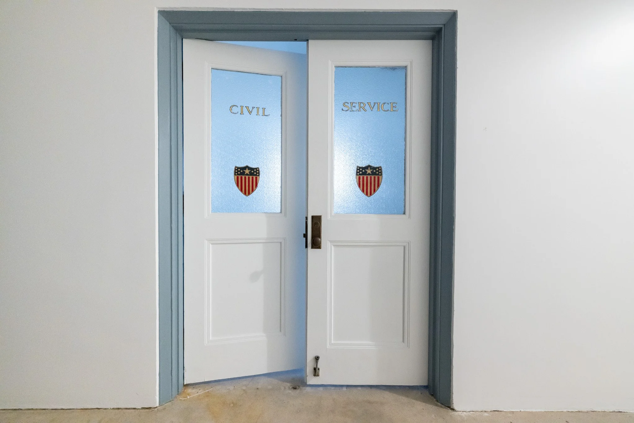 Double doors with frosted glass panes labeled 'Civil' and 'Service', each with a shield emblem featuring Stars and Stripes design.