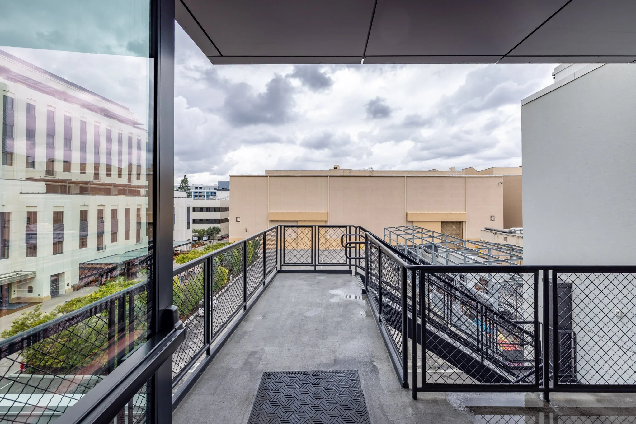 View from a balcony overlooking a cityscape with modern buildings and cloudy sky.