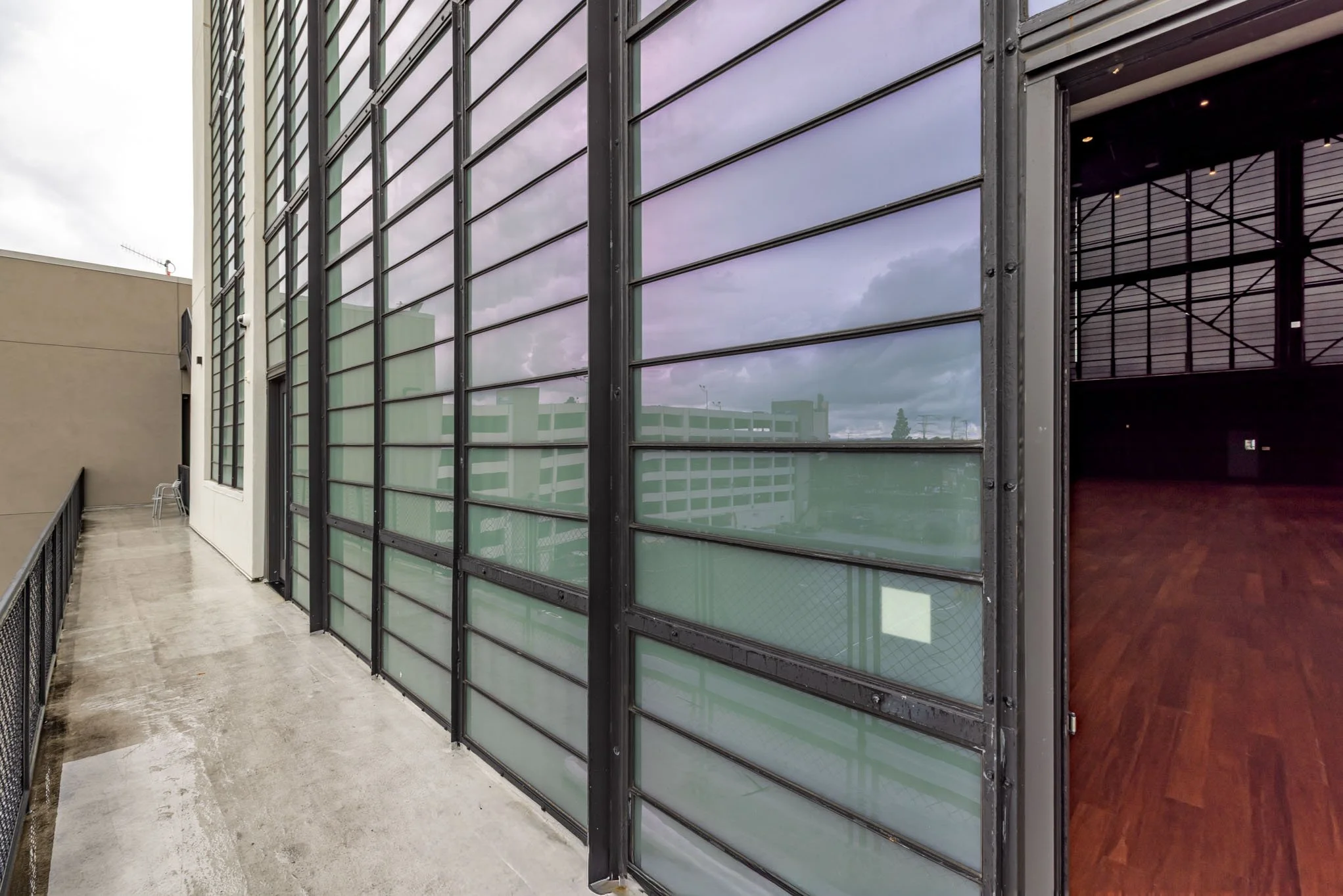 Exterior view of a modern building with large glass windows and an open door on a cloudy day.