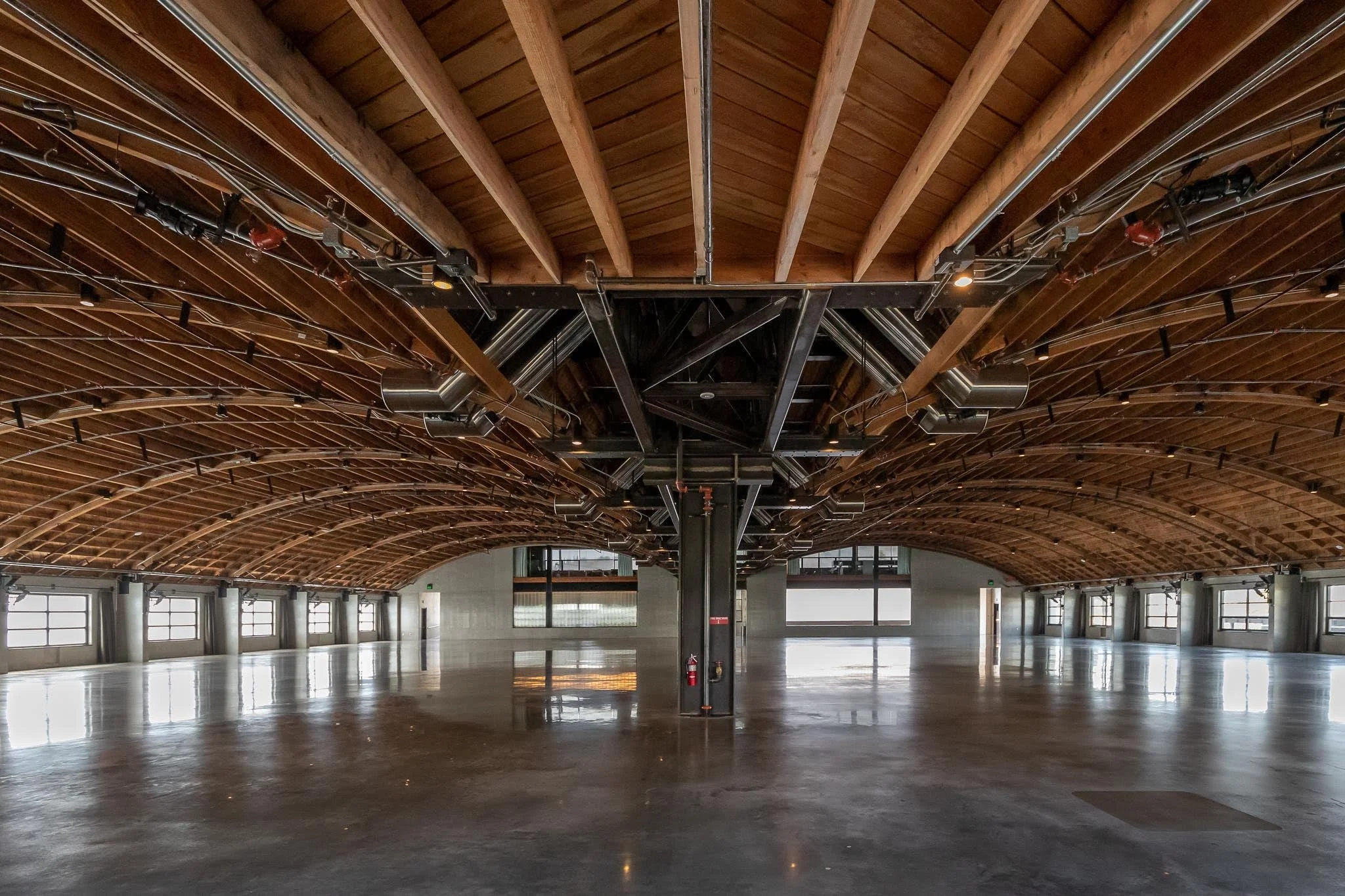 Empty industrial-style conference room with high wooden arched ceiling and large windows