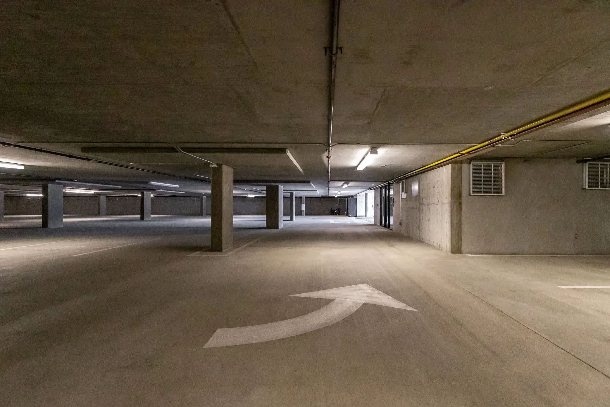 Empty underground parking garage with a white arrow painted on the floor indicating a left turn.