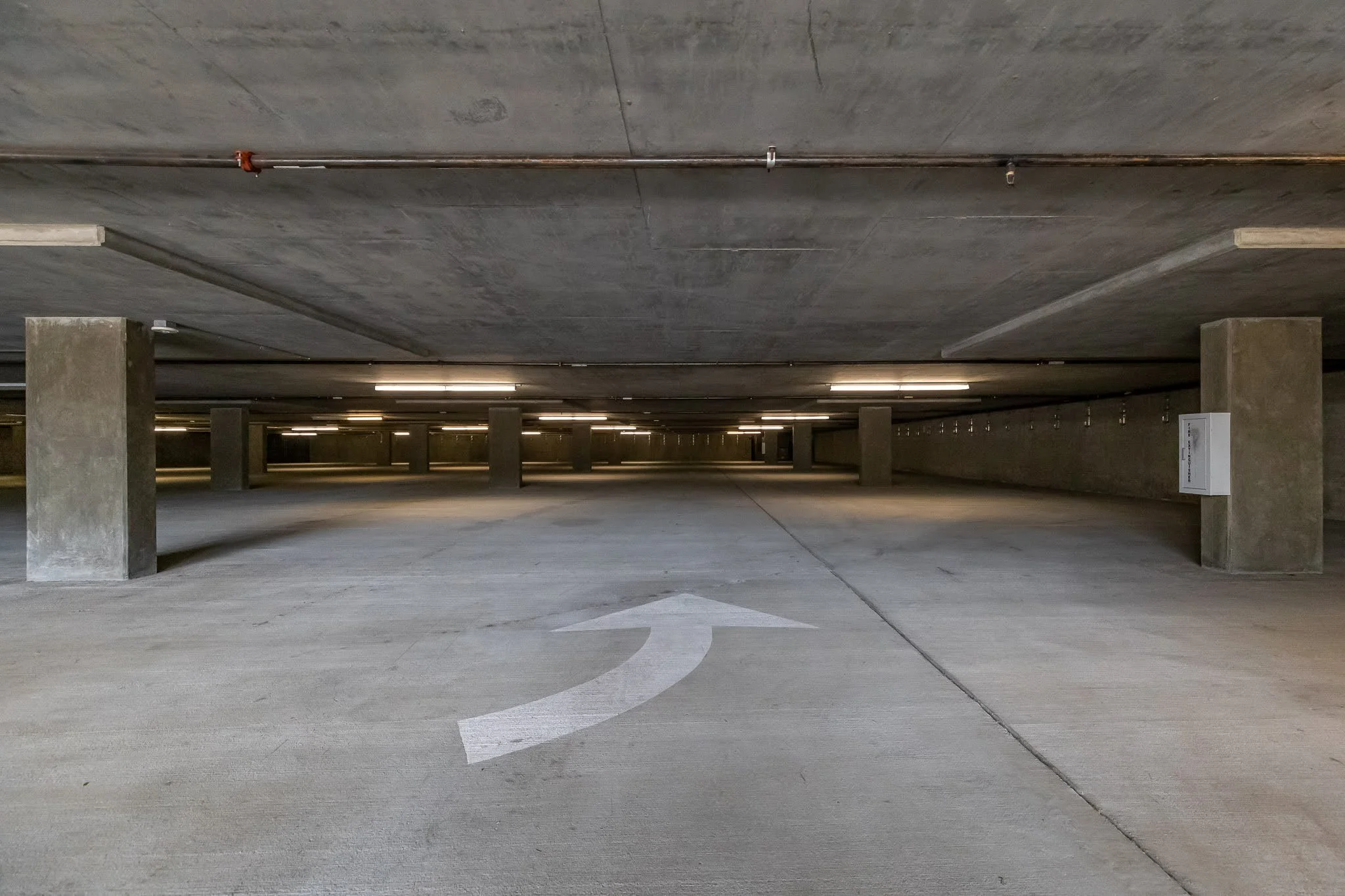 Empty underground parking garage with a white arrow painted on the floor indicating a turn to the left.