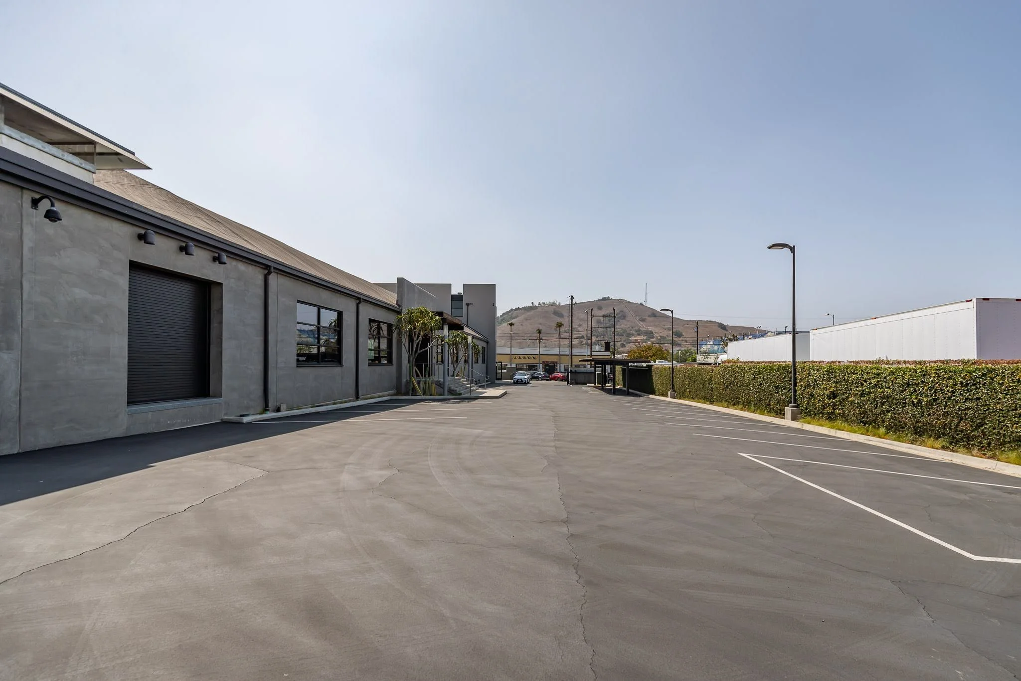 Empty parking lot outside of a commercial building with a mountain in the background.