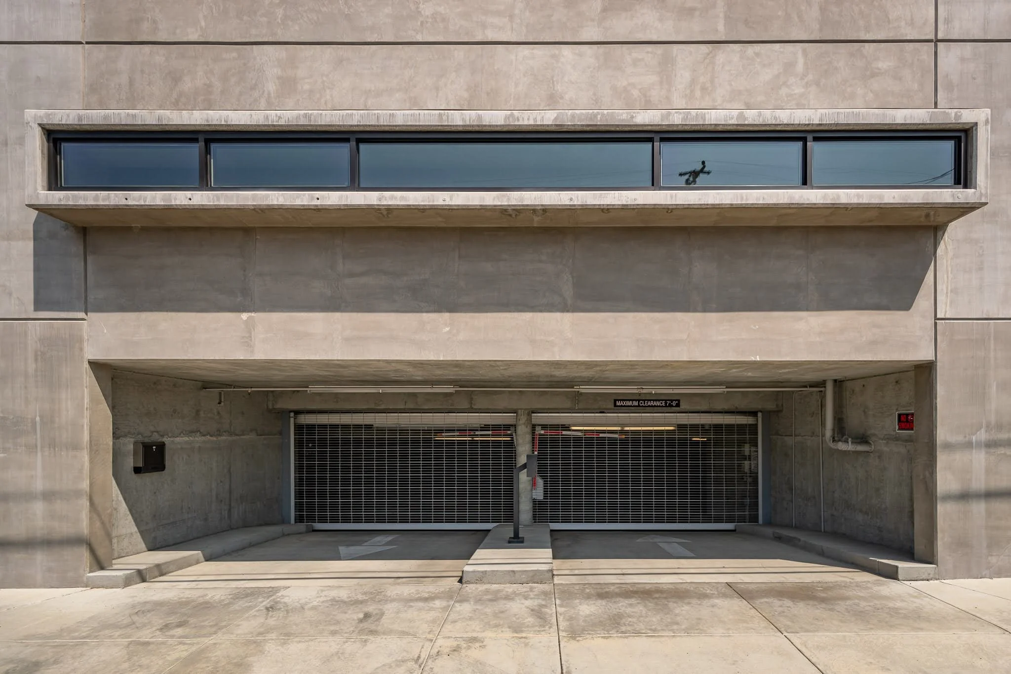 Empty parking garage entrance with a closed metal gate, concrete structure, and a small ramp leading into the garage.
