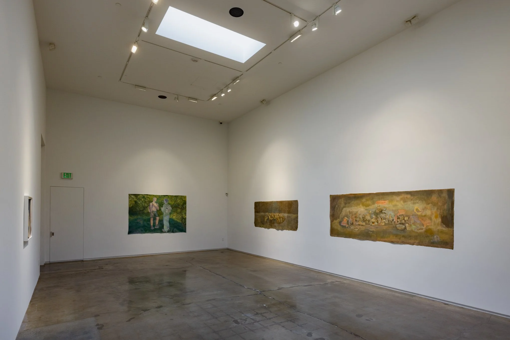 Contemporary art gallery with three large paintings on white walls, concrete floor, and skylight overhead.